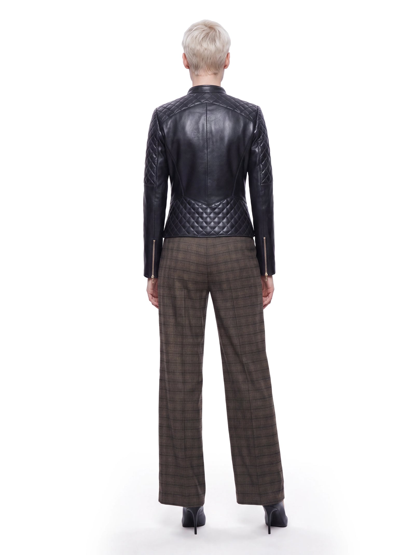 Schwarze Luxus Designer Lederjacke in der Rückansicht mit körpernaher, taillierter Silhouette. Rautenförmige Steppungen an Schulterpartie, Ärmeln und unterem Rücken sowie präzise Teilungsnähte und goldfarbene Reißverschlüsse an den Ärmelabschlüssen prägen das Design.