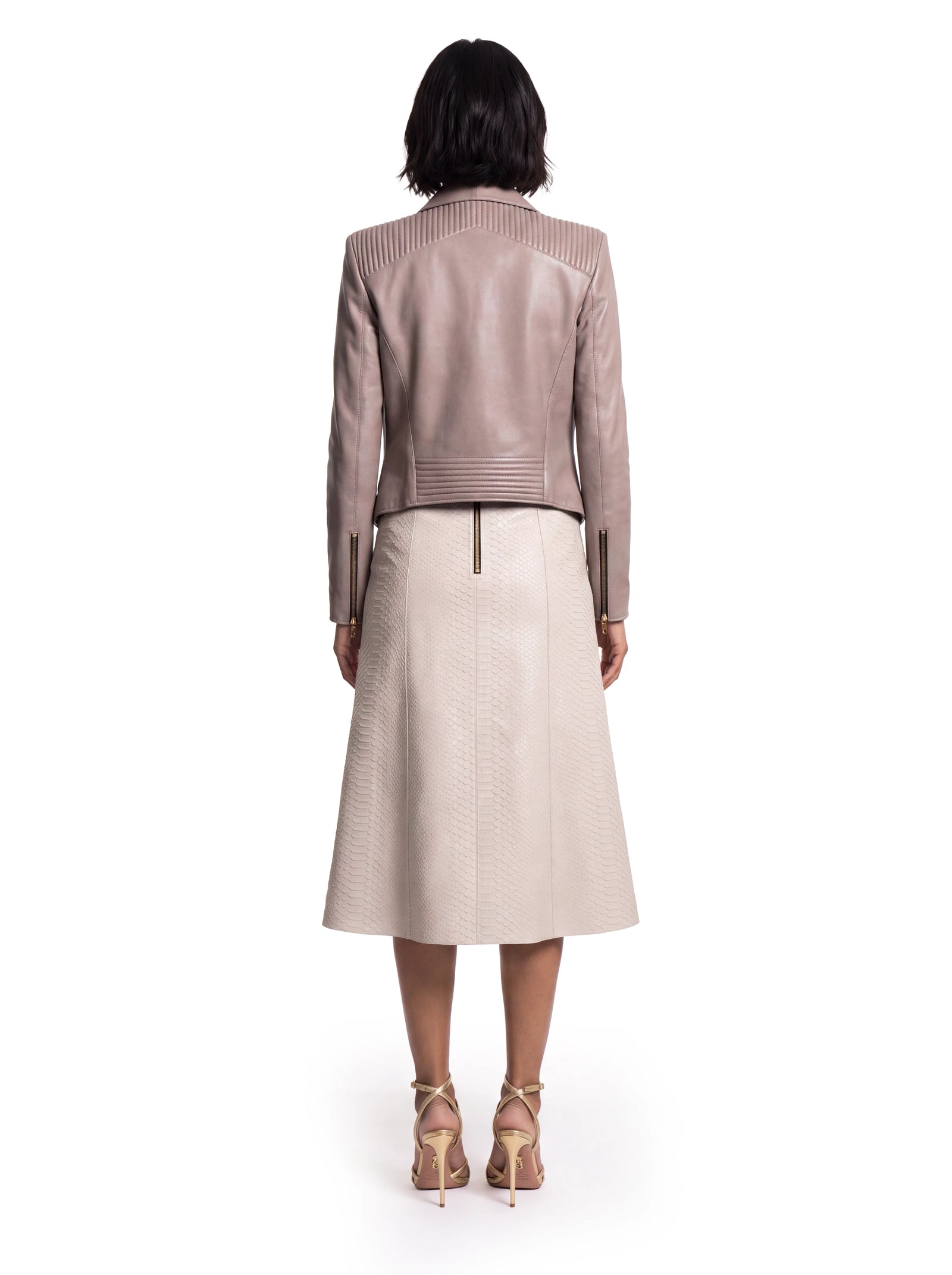 Beige Luxus Designer Lederjacke in der Rückansicht mit prägnanten Steppdetails an Schulterpartie und Saum. Die taillierte Schnittführung und feinen Teilungsnähte betonen die feminine Silhouette, während Reißverschlüsse an den Ärmelabschlüssen moderne Akzente setzen.