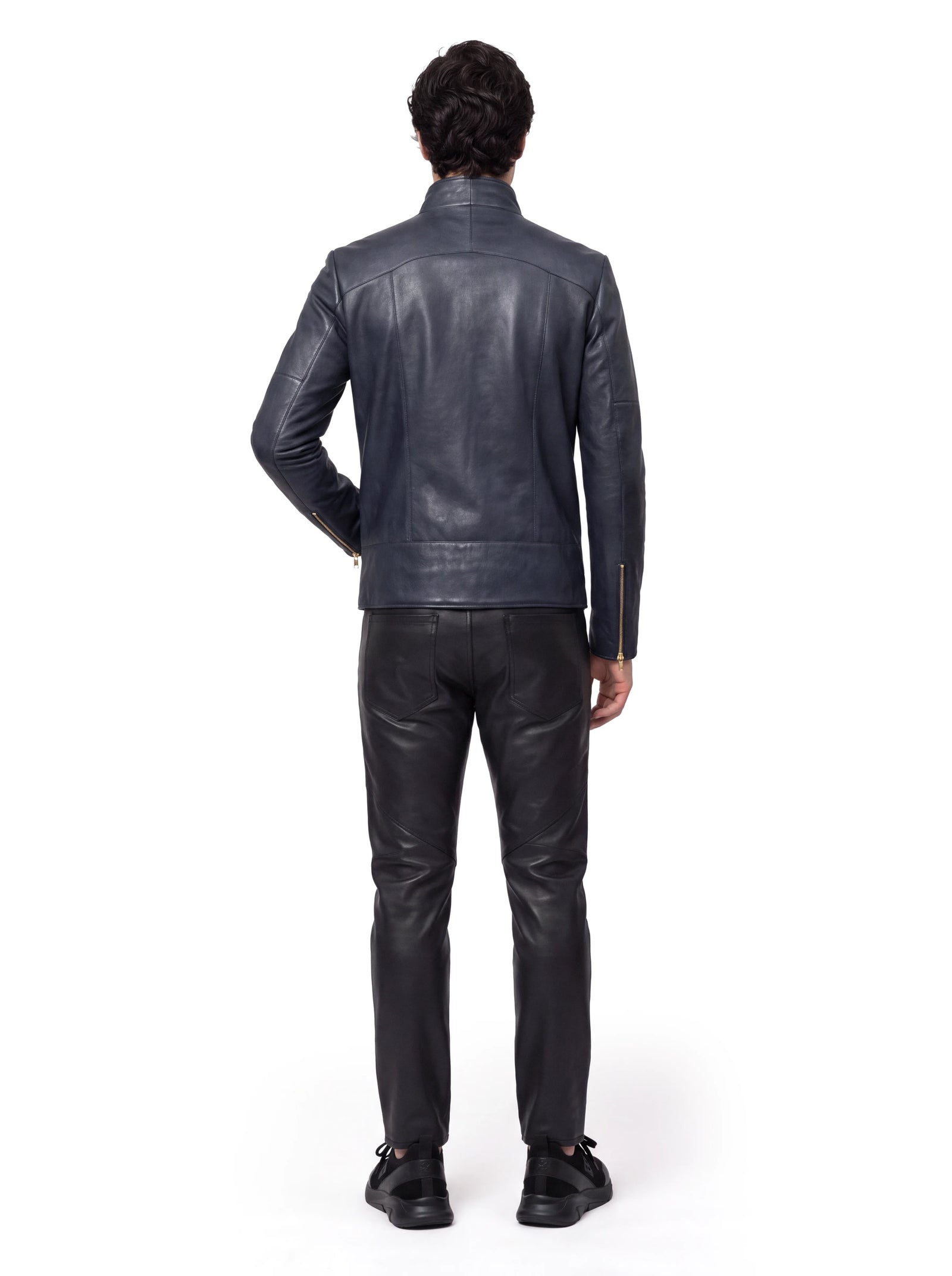Dunkelblaue Luxus Designer Lederjacke für Herren in der Rückansicht mit hohem Stehkragen und klarer, körpernaher Silhouette. Präzise Teilungsnähte strukturieren die Rückenpartie, während Reißverschlüsse an den Ärmelabschlüssen goldfarbene Akzente setzen.