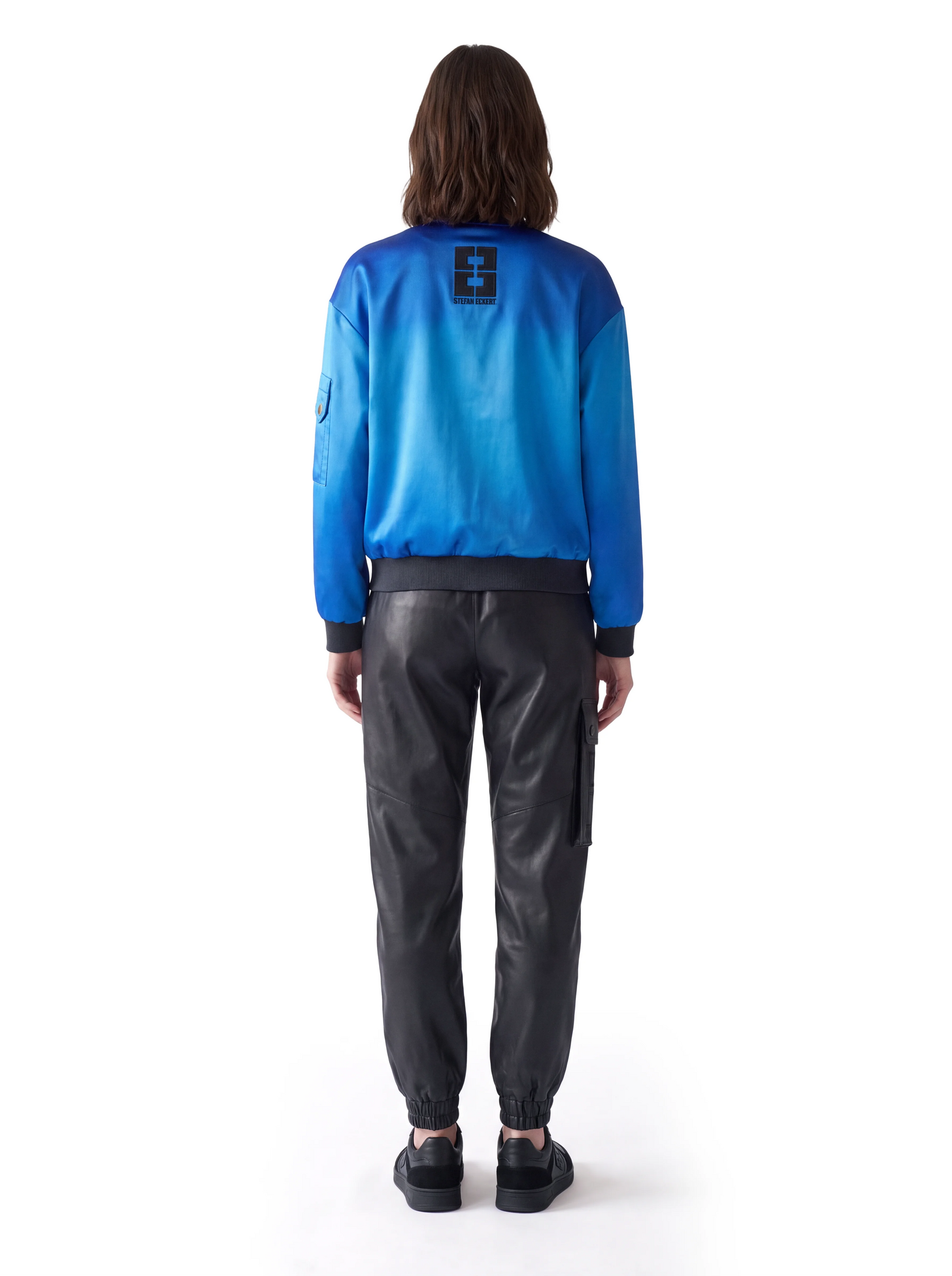 Schwarze Luxus Designer Lederhose in der Rückansicht mit locker geschnittener Silhouette und seitlich aufgesetzter Cargotasche. Markante Teilungsnähte und elastisch geraffte Beinabschlüsse verleihen der Hose einen modernen, funktionalen Designer-Look.