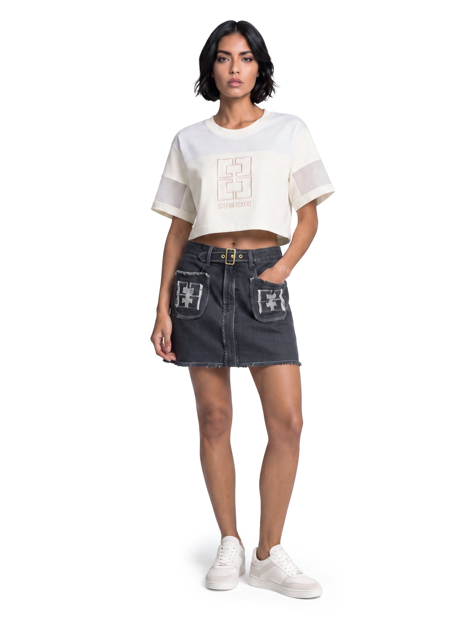 Dunkelgrauer Luxus Designer Jeansrock in A-Linien-Form mit markantem Fransensaum. Aufgesetzte Fronttaschen mit Monogram-Applikationen, sichtbare Kontrastnähte und ein integrierter Gürtel mit goldfarbener Schnalle prägen das Design.