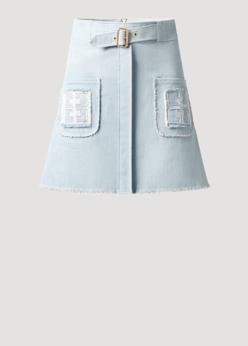 Monogram Minirock Vintageblau mit aufgesetzten Taschen und Gürtel von Designer Stefan Eckert. Erhältlich in Hamburg, London, New York, London und Paris. Denim skirt light blue with patch pockets and belt by designer Stefan Eckert. Available in Hamburg, London, New York, London and Paris.